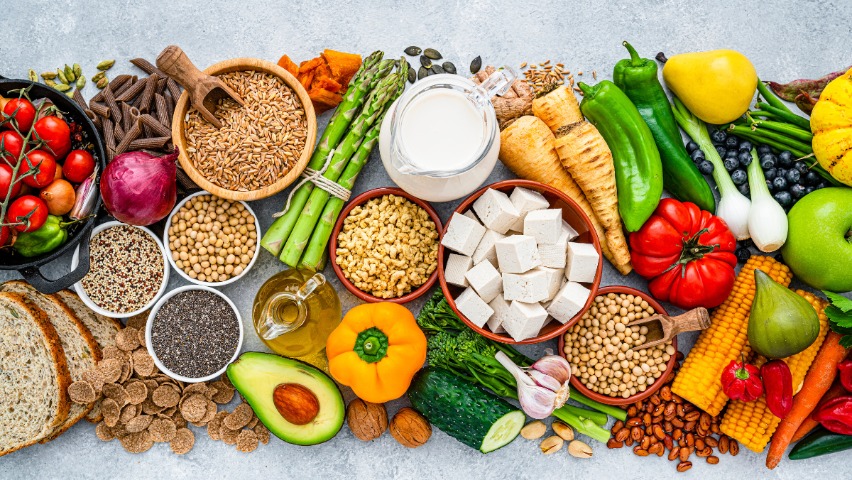 Assorted plant-based ingredients including grains, vegetables, legumes and tofu laid out on a table.