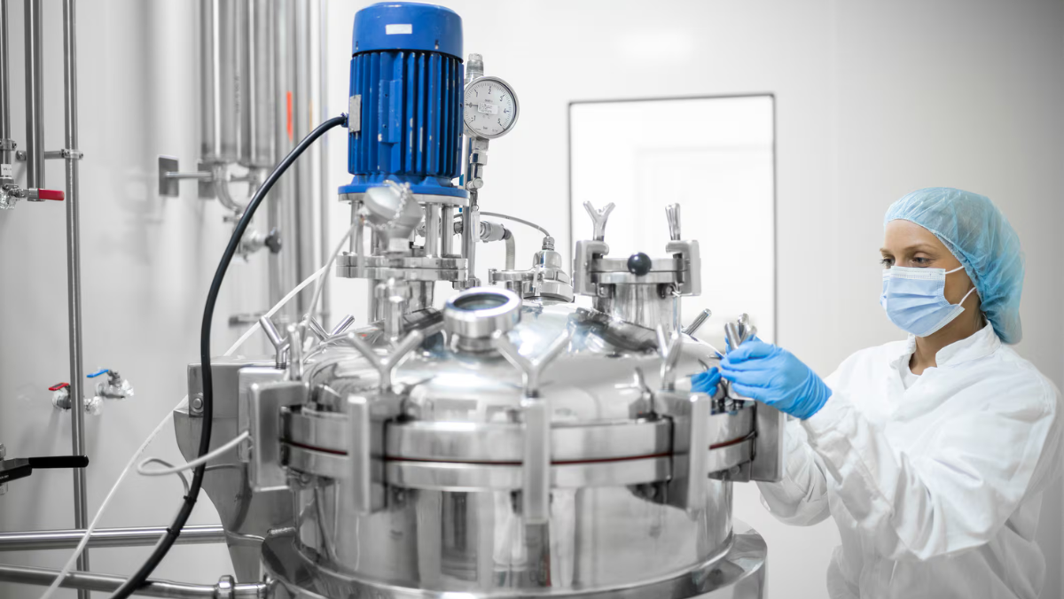 Biotech technician monitoring fermentation protein production in a controlled bioreactor