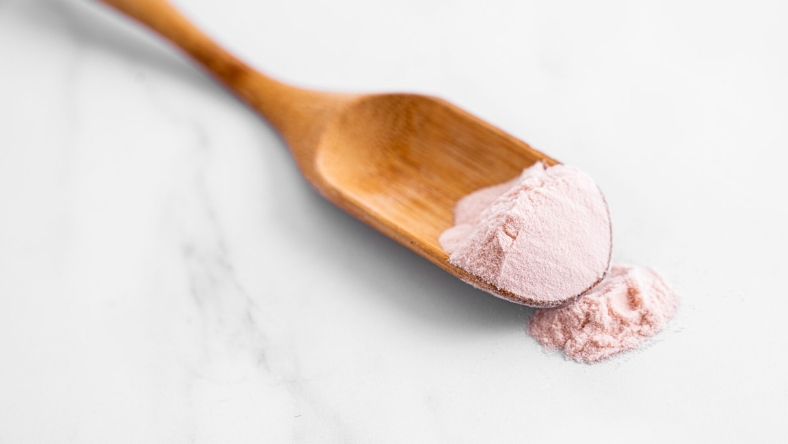 Close-up of lactoferrin protein powder in wooden spoon