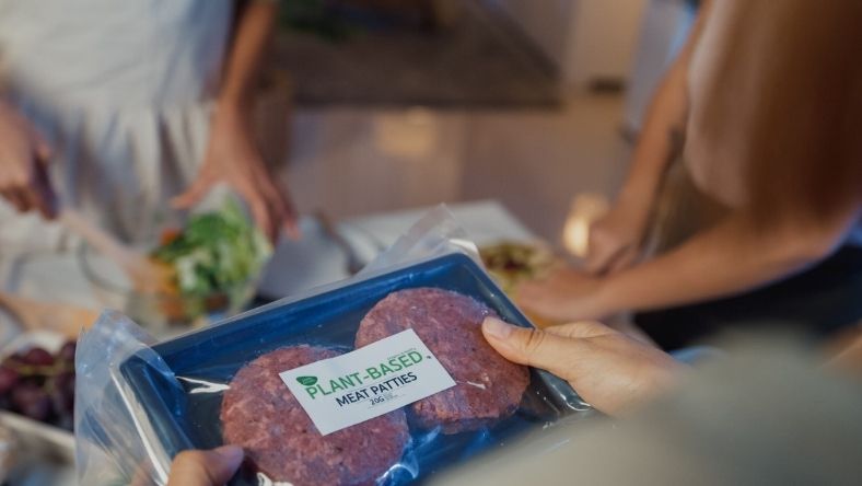 Hand holding sealed pack of plant-based meat patties