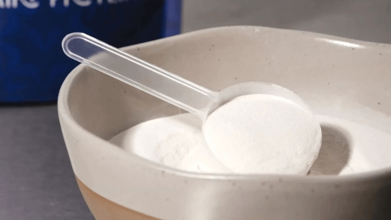 Scoop of white protein powder in a bowl